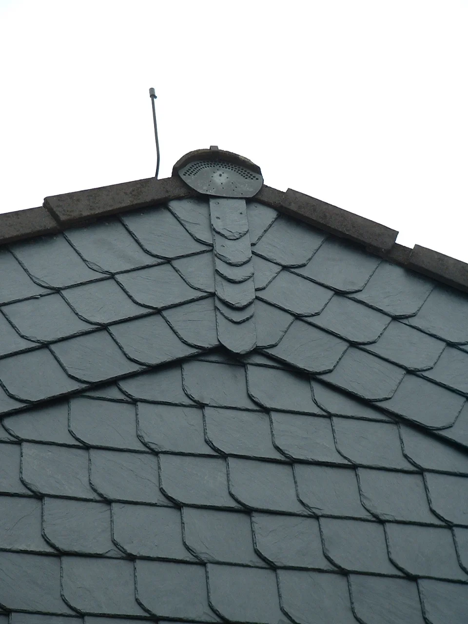 Giebelfläche in Schiefer-Schuppendeckung, die Zierreihe läuft in der Spitze auf die Lüfterhaube zu